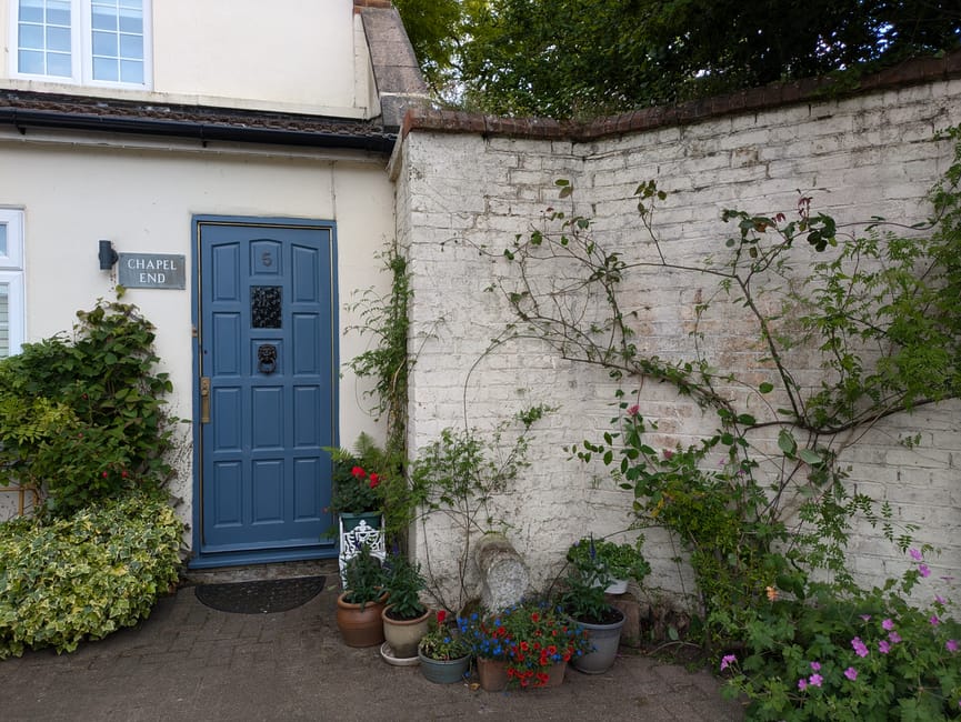 The image depicts the front entrance of a residential property with a blue painted door featuring decorative paneling and a metal lion head door knocker. To the left of the door, a sign reads 'CHAPEL 