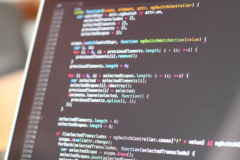 A close-up image of a computer screen displaying lines of colorful code, including syntax highlighted in green, blue, pink, and white text on a dark background. The screen occupies most of the frame, 
